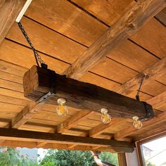 an outdoor area with wooden beams and lights hanging from the ceiling