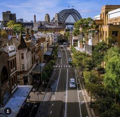 an aerial view of a city street with cars driving on it and the sydney bridge in the background