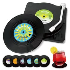 an old record player with six different colored discs and a drink in front of it