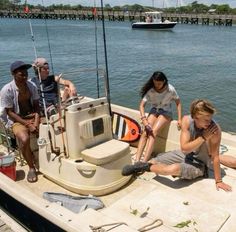 four people are sitting on the back of a boat