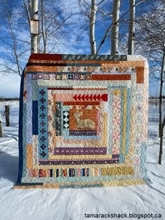 a quilt hanging from a tree in the snow