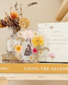 a glass vase filled with flowers sitting on top of a wooden table next to a book