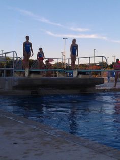 people in bathing suits standing on the edge of a swimming pool