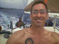 a shirtless man on a boat smiling at the camera