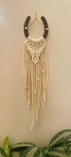 a wall hanging made out of macrame and leather with a wooden hook attached to it