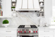 a stove top oven sitting inside of a kitchen next to white cabinets and counter tops