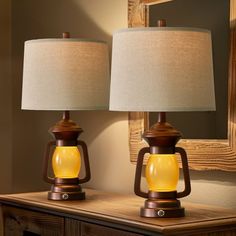 two lamps sitting on top of a wooden table next to a mirror and lamp shade