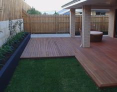 a wooden deck in the middle of a yard with a hot tub next to it