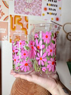 a person holding three glasses with pink flowers painted on them