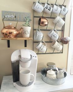 a coffee maker sitting on top of a counter next to a cup holder and mugs