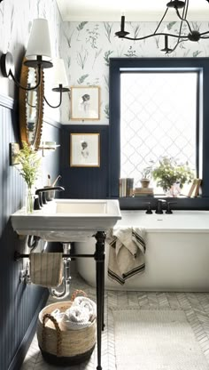 a bath tub sitting under a bathroom window next to a white sink and a mirror