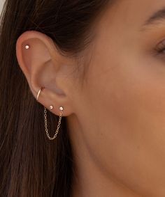 a close up of a woman's ear wearing a gold chain and pearl earrings