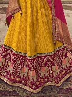 Let the festive charm and warmth reflect in your dressing with this scintillating outfit. This beautiful yellow color lehenga is made of viscose material adorned with sequin work, thread, and embroidery work with gorgeous elephant motifs. This sweet yellow lehenga comes with a red color blouse of viscose silk material designed with sequin, thread, and embroidery work. It also comes with a red color organza material dupatta crafted with zari weaving and bandhani print with precious lace border wo Yellow Sharara With Cutdana For Eid, Yellow Chinon Anarkali Set With Cutdana, Yellow Sharara With Dori Work, Yellow Anarkali Set With Dori Work For Eid, Yellow Anarkali Salwar Kameez With Dori Work, Yellow Anarkali Set With Zari Work, Designer Yellow Salwar Kameez With Dori Work, Yellow Floor-length Dupatta For Reception, Yellow Cutdana Sets For Reception