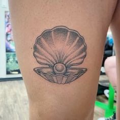 a woman's thigh with a black and white shell tattoo on it