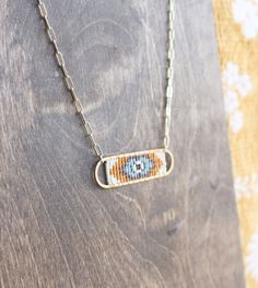 a beaded necklace is hanging on a wooden surface with a flowered cloth in the background