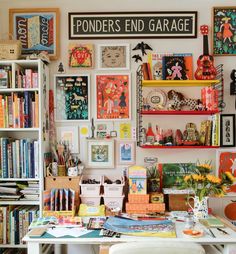 a room filled with lots of books and pictures on the wall next to a desk