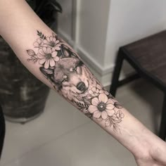 a woman's arm with flowers and a wolf tattoo on the left inner arm