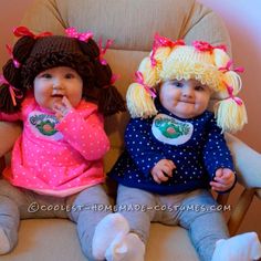 two baby dolls sitting next to each other on a chair