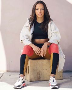 a woman sitting on top of a wooden box wearing leggings and sports bra