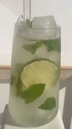 a glass filled with ice and lime on top of a table