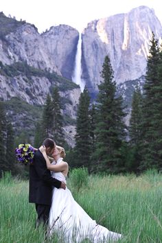 a bride and groom kissing in front of the yose falls at their wedding reception