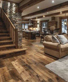 a living room filled with furniture next to a stone wall and wooden stairs in front of a kitchen