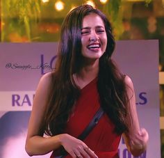 a woman in a red dress is smiling and holding a handbag on her shoulder