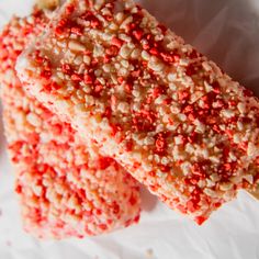 two pieces of cake sitting on top of a piece of wax paper with red sprinkles