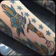 a person with a tattoo on their arm holding a pencil and an object in the shape of a rocket