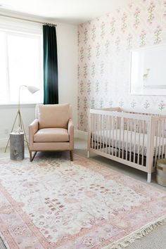 a baby's room with pink and green floral wallpaper