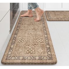 two rugs in the middle of a kitchen with one person standing on top of it