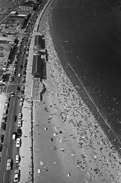 an aerial view of a beach with cars parked on the shore and buildings in the background