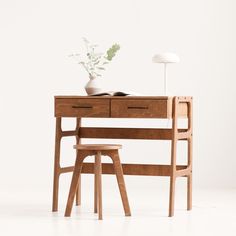 a wooden desk with two chairs and a plant