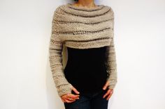 a woman standing in front of a white wall with her hands on her hips wearing a sweater