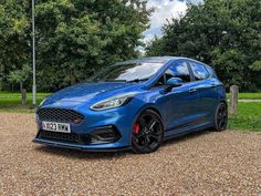 a blue car parked on top of a gravel road