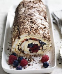 a roll is on a plate with berries and other desserts next to it,