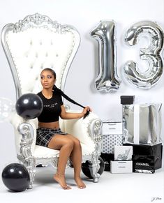 a woman sitting on a chair in front of balloons and presents for her 30th birthday