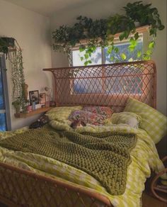 a bed sitting in a bedroom next to a window covered in green blankets and pillows