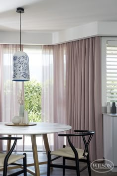 a dining table with two chairs and a vase on it in front of the window