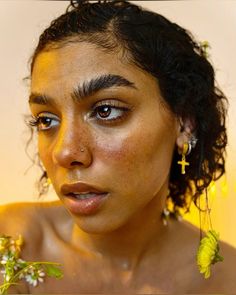 a woman with freckles on her face and flowers in her hair is looking at the camera