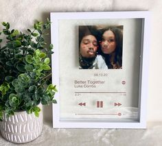 a white frame with two girls on it next to a potted plant and an mp3 player