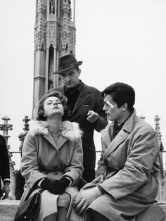 an old photo of two people sitting next to each other in front of a clock tower