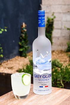 a bottle of grey goose vodka next to a glass with a lime slice on it