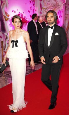 a man and woman in formal wear walking down a red carpet