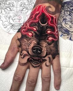 a man's hand with tattoos on it and a wolf face painted on the palm