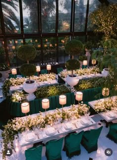 an indoor dining area with tables and chairs covered in green linens, lit by candles