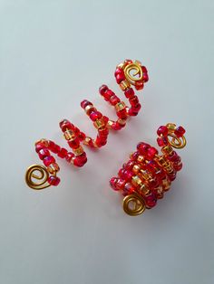 three red and gold beaded objects on a white surface