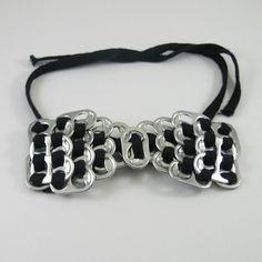 a black and silver bracelet on a white surface with a knot at the end that is attached to it