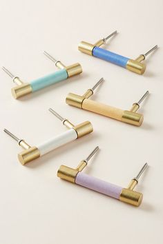 four different colored pins with metal tips on them, all lined up in the same row