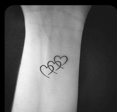 two hearts tattoo on the wrist, with one heart in the shape of three interlocks